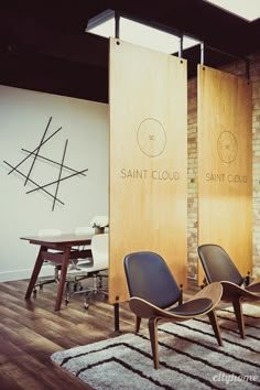 two chairs sitting next to each other on top of a hard wood floor in front of a brick wall