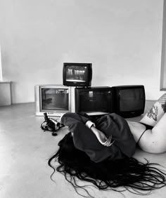 a woman laying on the floor in front of three tvs and two monitors,