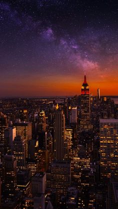 the city skyline is lit up at night with many stars in the sky above it