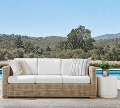 a couch sitting on top of a wooden floor next to a swimming pool with trees in the background