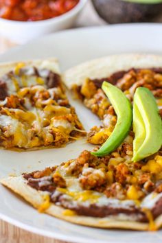 a close up of a plate of food with pizza and an avocado on it