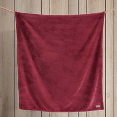 a red towel hanging from a rope on a wooden wall with wood planks in the background