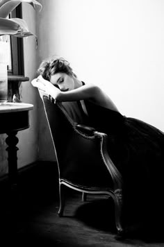 black and white photograph of a woman sitting in a chair with her head on her hand