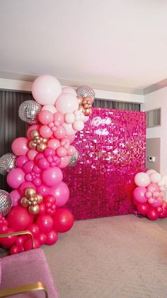 pink and gold balloons are hanging from the ceiling in front of a large mirror wall