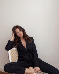 a woman sitting on top of a chair with her hand on her head and looking at the camera