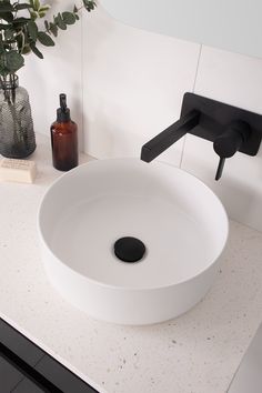 a white sink sitting on top of a bathroom counter next to a black faucet