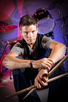 a man sitting on the floor with drums in front of him