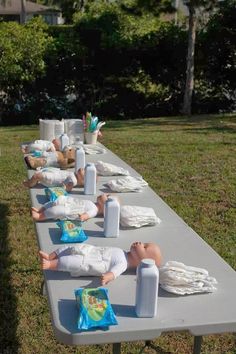 there are many people laying down on the long table in the yard with blankets and pillows