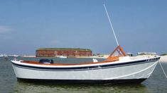 a small white boat floating on top of a body of water next to a sandy beach