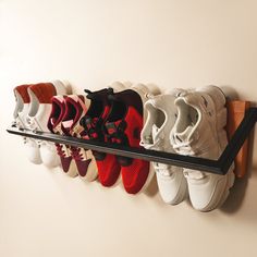 there are many pairs of shoes hanging on the wall and in front of them is a shoe rack