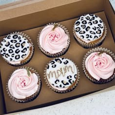 six decorated cupcakes with pink frosting and leopard print wrappers in a box