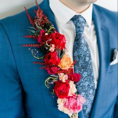 a man wearing a blue suit with red and orange flowers on his lapel flower