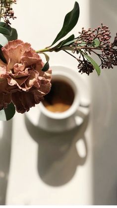 a vase filled with flowers next to a cup of coffee