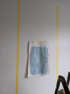 the wall is painted white and has yellow tape on it as well as a blue piece of paper