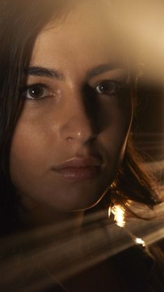 a woman looking at herself in the mirror with light shining on her face and hair