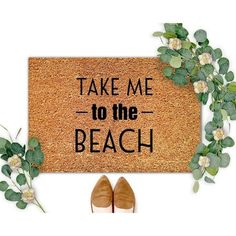 a door mat with the words take me to the beach on it next to shoes and flowers