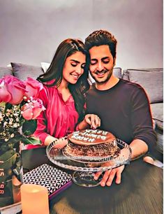 a man and woman sitting at a table with a cake