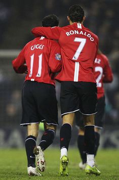 two soccer players in red and black uniforms are hugging each other on the field with their arms around one another