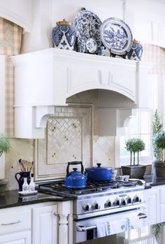 a stove top oven sitting inside of a kitchen next to a counter topped with plates