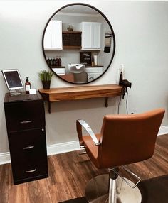 a mirror sitting on top of a wooden table next to a hair dresser and chair