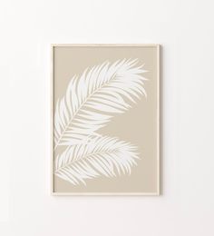 a white palm leaf on a beige background in front of a wall mounted art piece