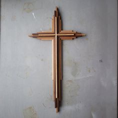 a wooden cross hanging on the wall in a room with white walls and concrete flooring