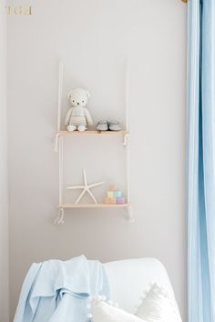 a teddy bear sitting on top of a shelf next to a white couch in a living room