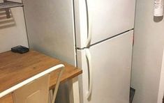 a white refrigerator freezer sitting next to a wooden counter top on a kitchen floor