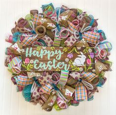 a wreath with the words happy easter painted on it and decorated with colorful fabric bows