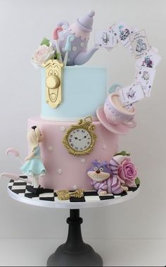 there is a pink and blue cake on top of a black stand with decorations around it