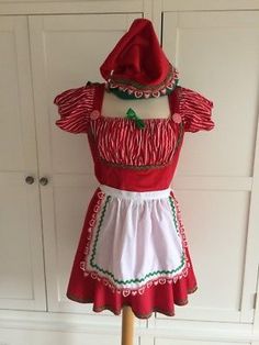 a woman's red and white dress on a mannequin stand in front of cupboards