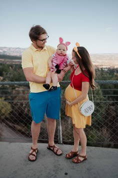 a man and woman holding a baby while standing next to each other