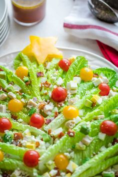 a salad with lettuce, tomatoes and other toppings on a white plate