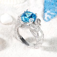 Unique and shimmering, this beautiful mermaid ring adds out-of-this-world sparkle to your style. Beautifully handcrafted in fine sterling silver, this stunning design showcases a sparkling aquamarine color stone at the center, while coral-shaped prongs add more glamour to the design.Glistening with detail, a lifelike mermaid shimmers with more stones, completing ring's distinctive shank. A heart cut stone sparkles between its beautiful tail, expressing all the love you hold in your heart.Carat Weight: 6.2 ctStone Size: 10 mmStone Type: Jeulia® StoneNumber of Stones: 1 Stone Color: Aquamarine BlueStone Shape: RoundCarat Weight: 1.574 ctStone Size: 0.8,1,1.1,1.3,1.5,3*3 mmStone Type: Jeulia® StoneNumber of Stones: 145 Stone Color: Diamond WhiteStone Shape: Round, HeartWeight: 10 gWidth: 12.5 Luxury Light Blue Rings For Women, Luxury Ocean-inspired Rings For Gift, Amethyst Mermaid Ring, Mermaid Rings, Aquamarine Mermaid, Memorable Jewelry, Couples Vintage, Goddess Of The Sea, Aquamarine Color