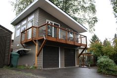 a two story house with a deck and garage in the front yard, surrounded by trees