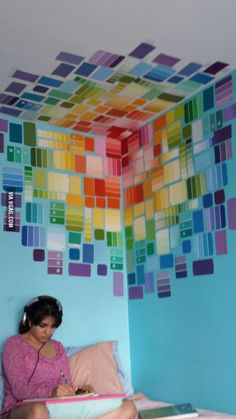 a woman sitting on top of a bed in front of a colorful wallpaper mural