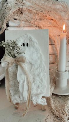 a white teddy bear holding a bouquet of flowers next to a lit candle