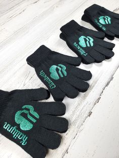 five black gloves with green logos on them sitting on a white table next to each other