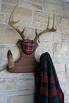 a deer head mounted to the side of a brick wall next to a coat rack