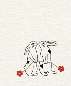 two rabbits sitting next to each other on top of a piece of paper with red flowers