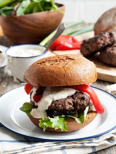 a hamburger with lettuce, tomato and cheese on it sitting on a plate