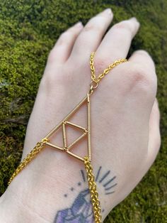 a person wearing a gold chain bracelet on their arm with an arrow charm attached to it