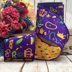 two purple and yellow fabric covered vases with flowers in the background on a wooden table