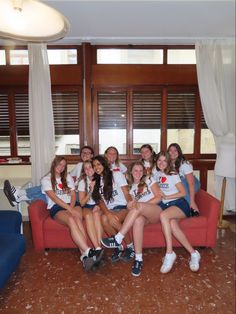 a group of young women sitting on top of a red couch next to each other