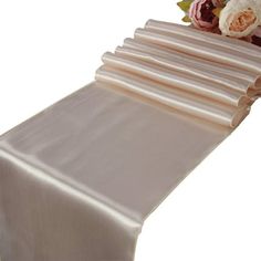 the table runner is lined up with white linens and pink flowers on each side