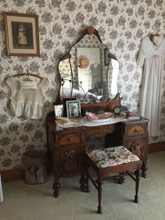 an antique dressing table with mirror, stool and pictures on the wall in front of it