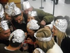 a group of people with tinfoil on their heads are looking at something in front of them