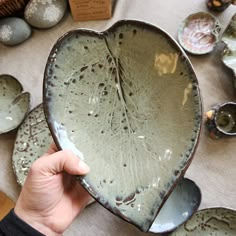 a person holding up a large bowl in front of other plates and bowls on a table