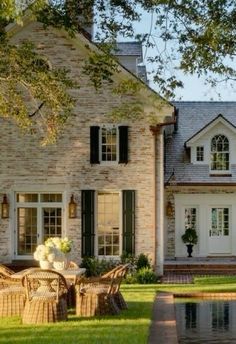 a large brick house sitting next to a pool in the middle of a lush green field