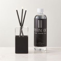 a bottle of perfume next to a glass with reeds in it